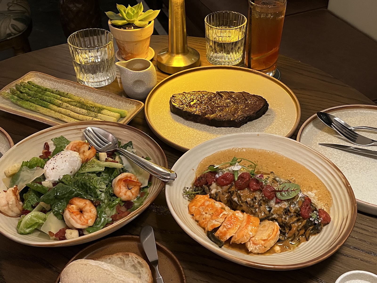 Bàn tiệc: bít tết, salad tôm, mì tôm hùm, măng tây