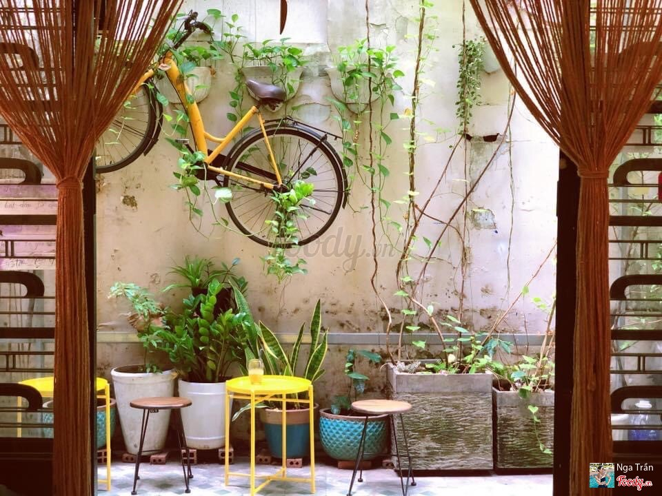 The courtyard with the yellow bicycle on the wall and mustard stools