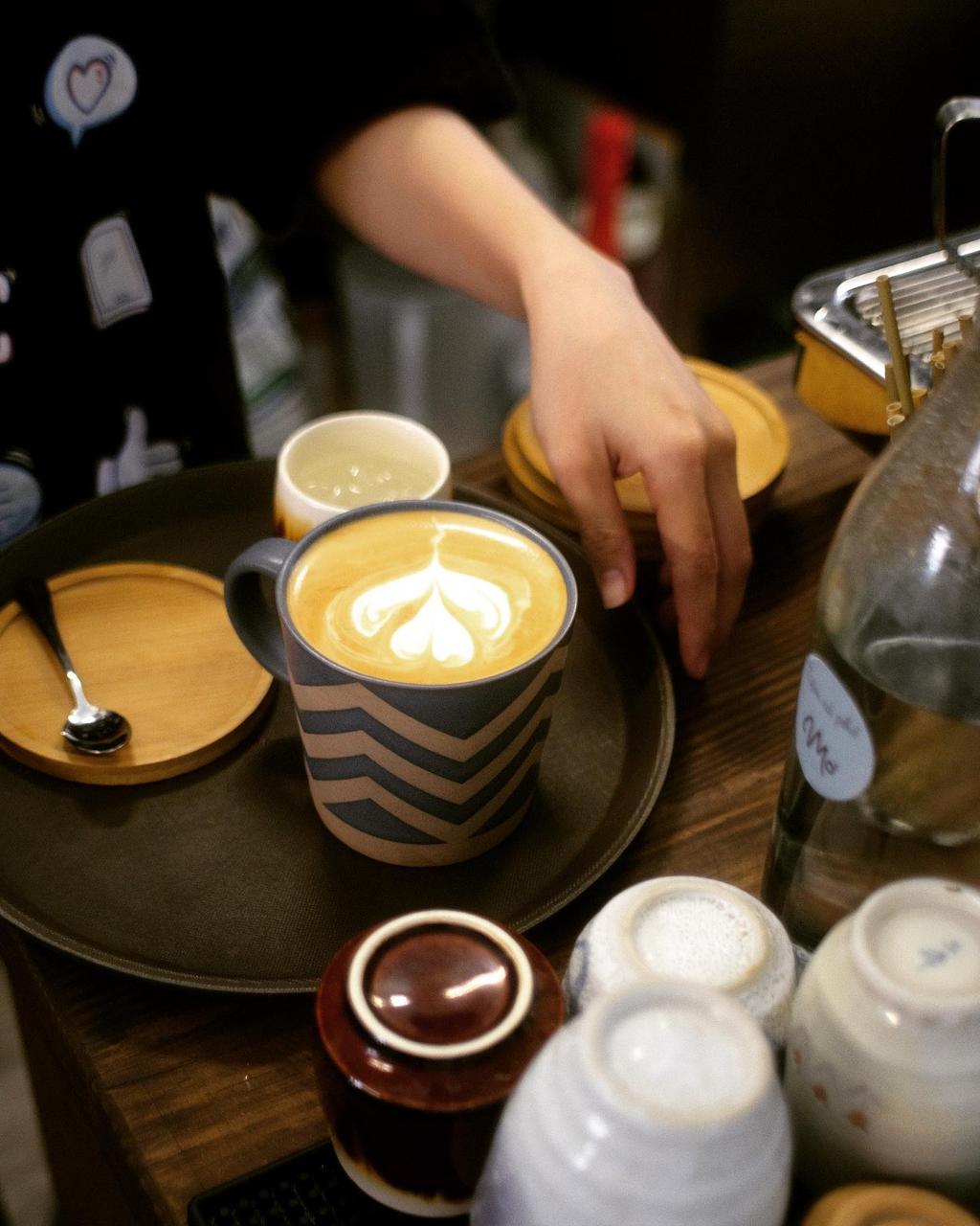 Ly latte với họa tiết latte art trong tách gốm men tại quầy bar