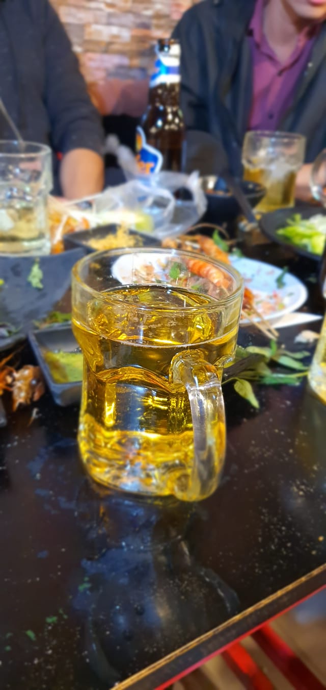 Cốc bia và đĩa xiên nướng trên bàn đêm