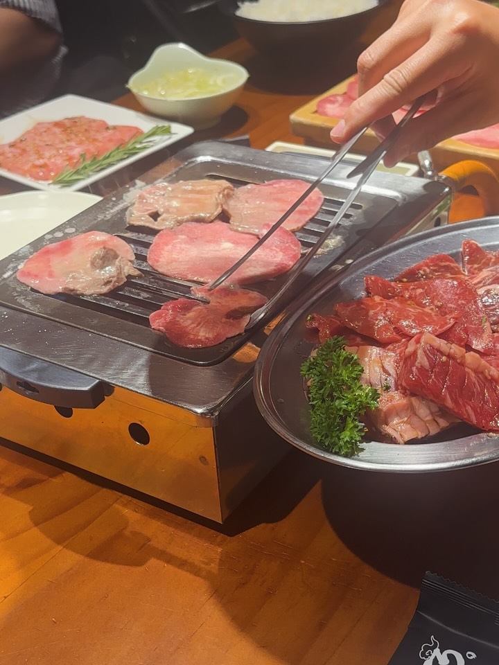 A diner grilling wagyu on the tabletop grill — the yakiniku moment