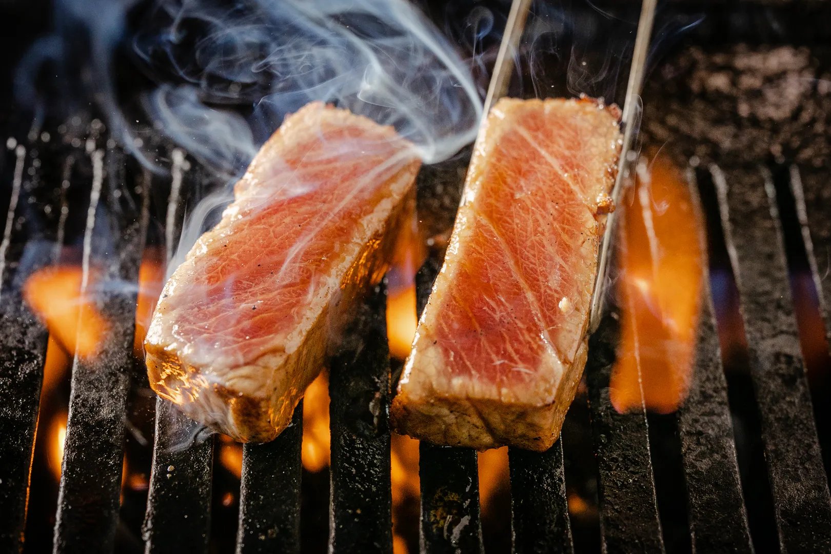 Tuna steaks searing over open charcoal flame