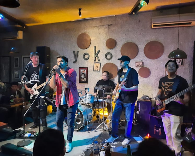 Yoko — ban nhạc với ca sĩ áo đỏ trước tường đĩa than