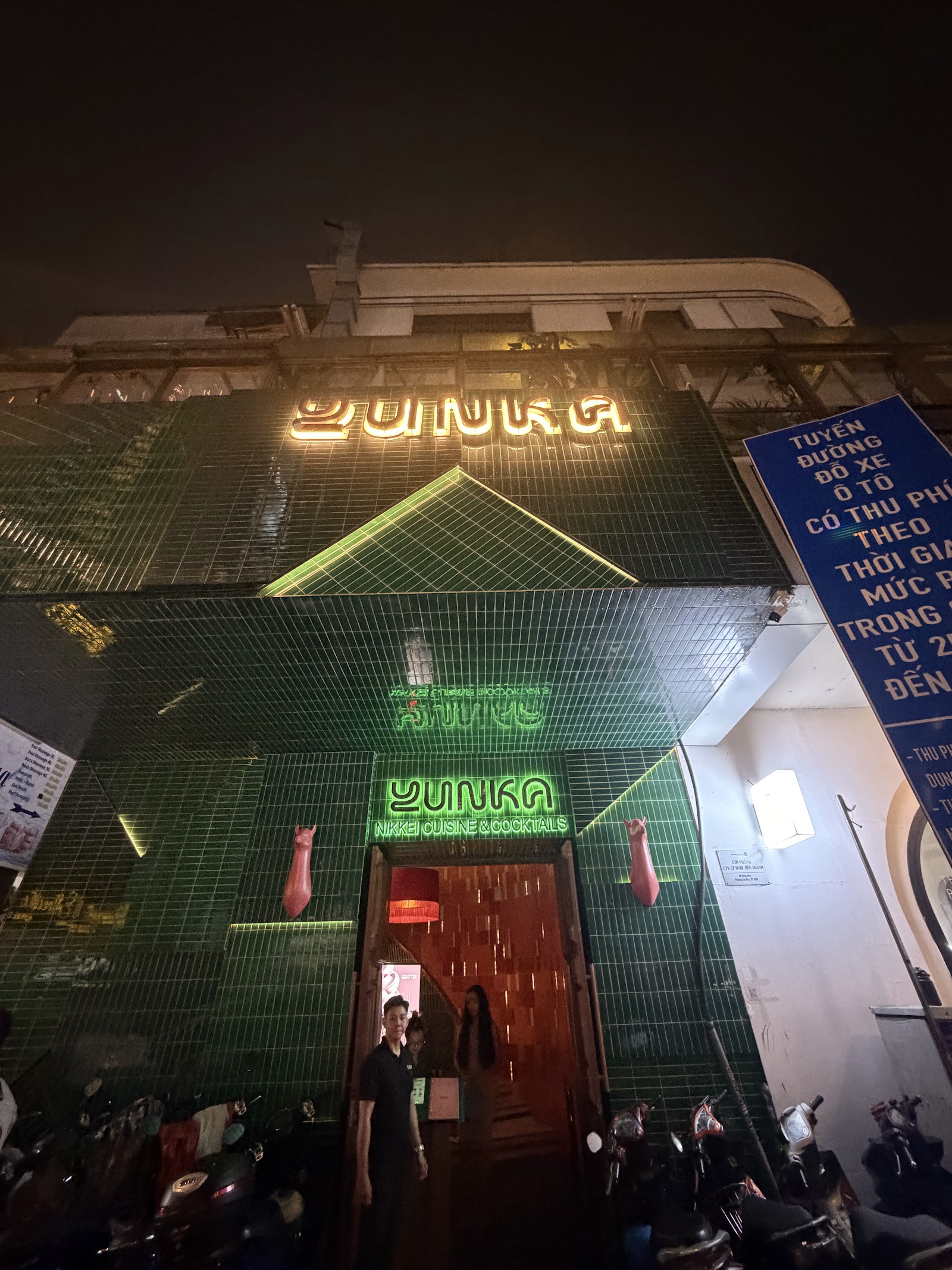 Mặt tiền Yunka về đêm — gạch xanh và biển hiệu neon YUNKA